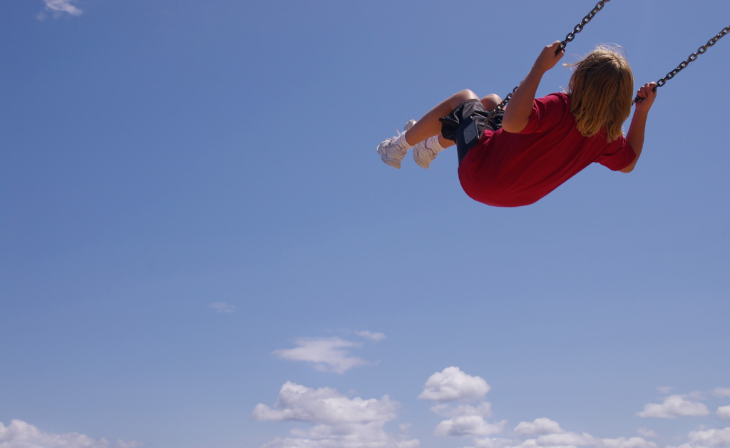 Child playing on a swing in the sky.