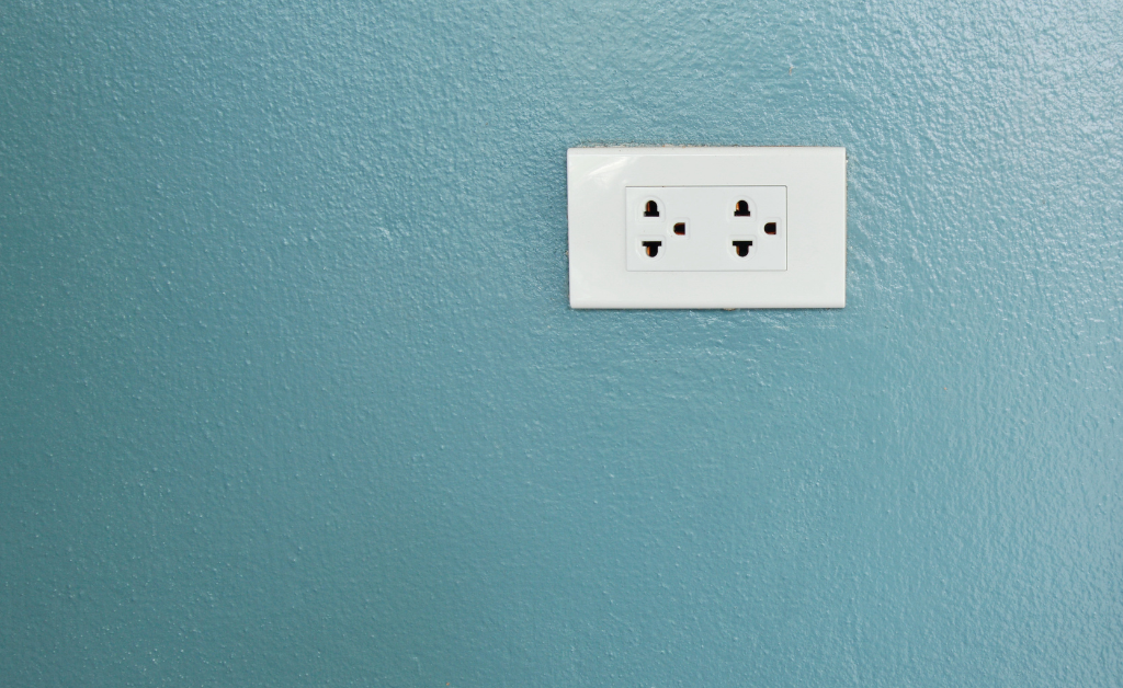 Electrical socket on a teal-colored wall.