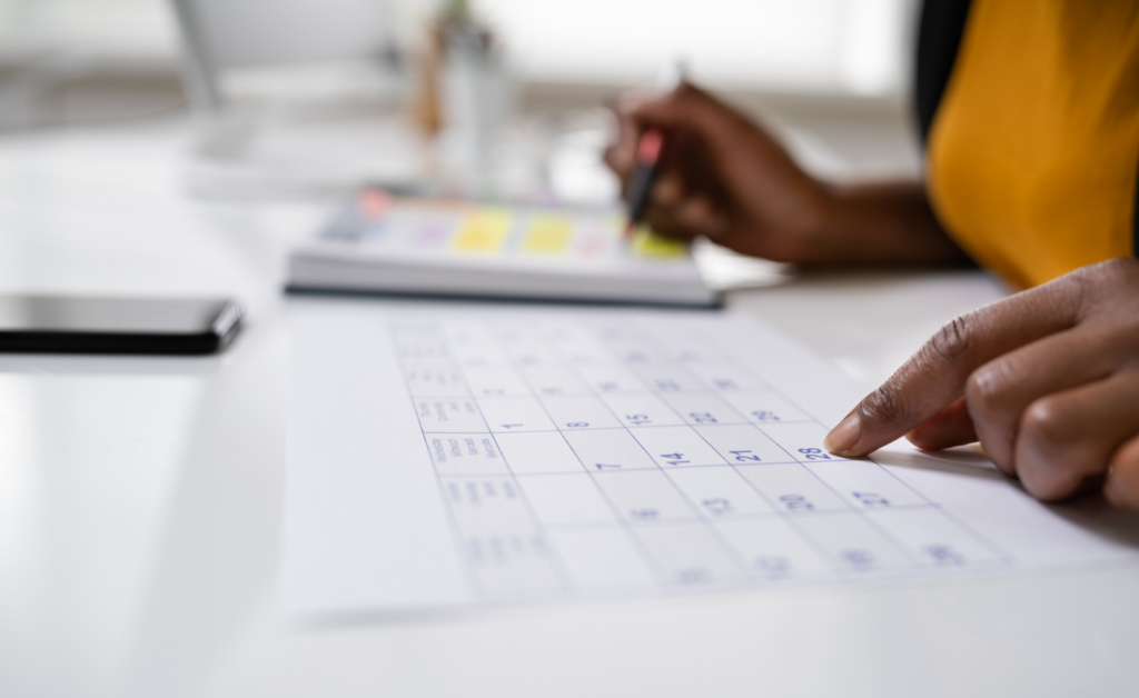 Woman pointing to calendar on a desk.