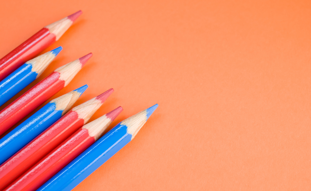 Orange and blue colored pencils against an orange background.
