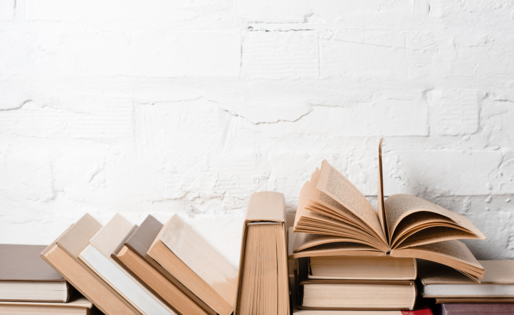 Hardback books against a white brick wall.