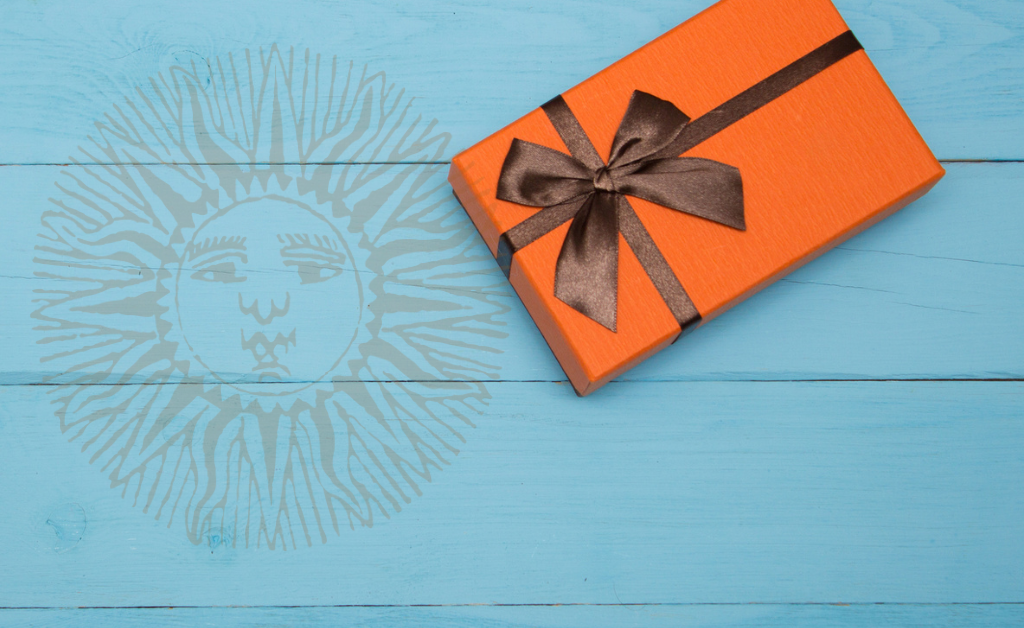 Orange gift on teal table with sun logo in background.